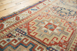 Antique Moghan Kazak runner: geometric gul with brick red, sky blue, and ivory floral motifs.