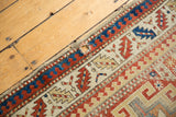 Antique Moghan Kazak runner with geometric motifs, rich colors, and reinforced interior hole.