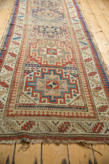 Antique Moghan Kazak rug runner with a frayed end and colorful geometric motifs.