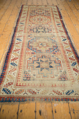 Antique Moghan Kazak runner with geometric gul medallions, brick red, sky blue, and visible wear.