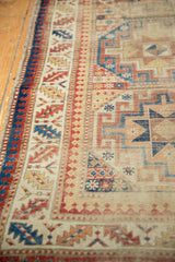 Antique Moghan Kazak rug runner's geometric border, colorful patterns, and visible side tatter.