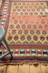Geometric border of antique Caucasian rug with red, blue motifs and tattered ends.