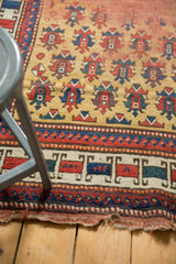 Antique Caucasian rug's ivory border with red and blue geometric motifs and worn, tattered end.