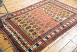 Geometric red, blue, green, ivory block border with tattered fringe on an antique Caucasian rug.