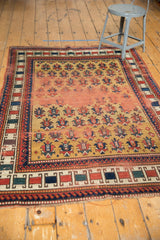 Lower border detail of antique Caucasian rug, with red, blue, green geometric blocks and gold field.