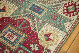 Textured hand-knotted pile with reciprocating geometric patterns in maroon red and celadon.