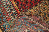 Corner of Vintage Kurdish Hamadan rug, showing hand-knotted pile, tattered ends, and woven foundation.