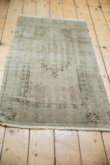 Distressed Oushak rug's faded dusty blush patterns, low shorn pile, and fringe.