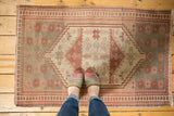 Distressed Oushak rug showing abrash, beige, cranberry floral and stepped geometric motifs.