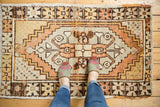 Distressed Oushak rug, low pile texture with geometric medallion in tangerine, saffron, and ivory.