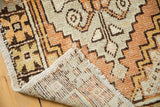 Distressed Oushak rug's folded corner shows low pile, geometric tangerine, saffron pattern, and reverse.