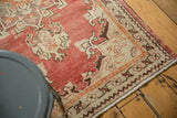 Distressed Oushak rug corner: antique ivory border with tangerine accents and fringe.