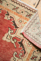 Distressed Oushak rug corner displaying worn brick red pile and hand-knotted foundation.
