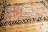 Distressed Oushak rug corner; charcoal, tangerine floral border and blush field.