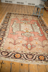 Distressed Oushak rug's meandering floral border in charcoal, tangerine, and ivory, revealing worn pile.