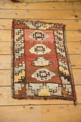 Distressed vintage Oushak rug mat corner, featuring barber pole border, geometric patterns, and fringed end.