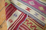 Folded vintage Jijim rug with geometric motifs, revealing detailed hand-woven texture and aubergine, red, ivory bands.
