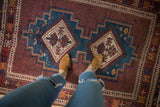Overhead view of a vintage Afshar rug's blue diamond medallion and detailed cherry red field.