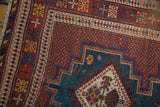 Intricate geometric borders in cherry red, blue, and gold on a vintage hand-knotted Afshar rug.