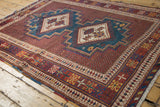 Angled perspective of a vintage Afshar rug's geometric diamond medallions and intricate red field.