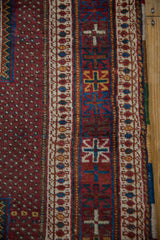 Close view of the geometric border patterns in red, blue, and ivory on a vintage Persian Afshar rug.
