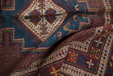 Intricate diamond medallion on the sky blue ground of a folded vintage Persian Afshar rug.