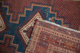 A vintage Afshar rug corner folded over, showing the front pile and hand-knotted back.