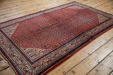 Vintage Mir Sarouk rug corner: traditional rust red boteh field, navy border, foundation wear.