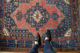 Vintage Kurdish Bijar rug with geometric navy medallion, brick red field, scrolling vinery.