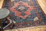 Vintage Kurdish Bijar rug's geometric brick red medallion, navy vinery field, and fringe.
