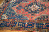 Kurdish Bijar rug detail: navy blue border with stylized floral motifs, brick red tones, and worn texture.