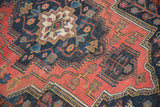 Vibrant geometric pattern in navy, brick red, and ivory with visible pile wear.