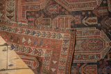 Folded Antique Qashqai rug showcasing terracotta geometric border, navy blue field patterns, and fringe.