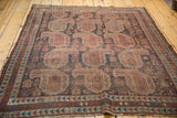 Antique Qashqai rug corner: geometric border, secured fringe, muted navy, terracotta, ivory.