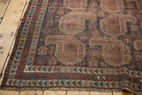 Antique Qashqai rug corner: geometric borders in terracotta, navy, and ivory with fringe.