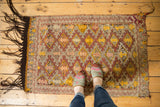 Upper left corner of vintage Jijim rug, hooked diamond patterns, zigzag border, dark fringe.