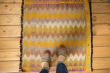 Vintage Jijim rug's right border, black fringe, and gold, ivory, purple zigzag pattern.