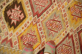 Vintage Jijim rug's hand-knotted texture and geometric starburst diamonds in beige, raspberry, gold.