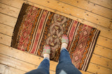 Densely ornamented geometric bands in chocolate, ivory, raspberry, and gold on a vintage Jijim runner.