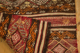 Folded vintage Jijim rug detail: patterned, plain bands in brown, red, gold, ivory.