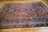 Low pile vintage Shiraz carpet corner with blue medallion and rust field patterns.