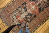 Vintage Malayer rug segment: navy stepped medallion, vinery, pinwheel motifs, and uneven wear.