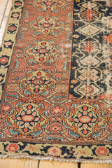 Vintage Malayer rug detail: terracotta pinwheel motifs, vinery, and worn navy field showing visible knot heads.