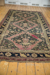 Antique Karabagh carpet's worn end, displaying short fringe, dark navy floral border, and geometric field.