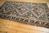 Corner of antique Karabagh carpet, showing dark navy floral border and serrated aubergine field.