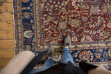 Vintage Kerman carpet: allover cherry red floral field, navy border, visible wear underfoot.