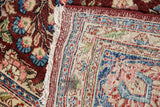 Tattered fringe, hand-knotted back, and worn floral pile of a vintage Kerman carpet.