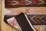 Vintage Jijim rug's charcoal black plain weave back contrasted by vibrant striped patterns.