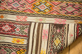 Folded vintage Jijim rug reveals raspberry geometric patterns and contrasting striped plain weave reverse.