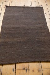 Secured end of the hand-woven Vintage Turkish Kilim, with varying chocolate brown tones.
